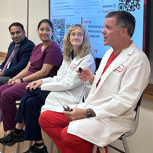 Four Stony Brook faculty sitting on stools at the front of a classroom