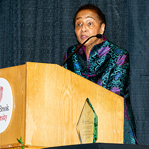 Dr. Reneida Reyes addresses the crowd at an on-stage podium